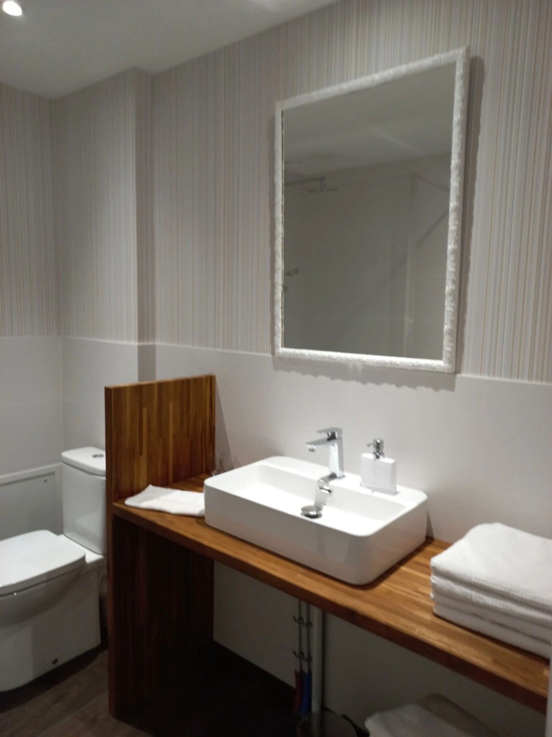 Une salle de bain moderne avec un meuble-lavabo en bois, un grand miroir et un lavabo blanc.