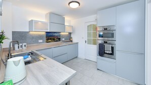 Una cocina moderna con armarios grises, electrodomésticos de acero inoxidable y lavavajillas integrado.