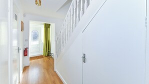 Un pasillo con una puerta blanca, un extintor y una cortina verde.