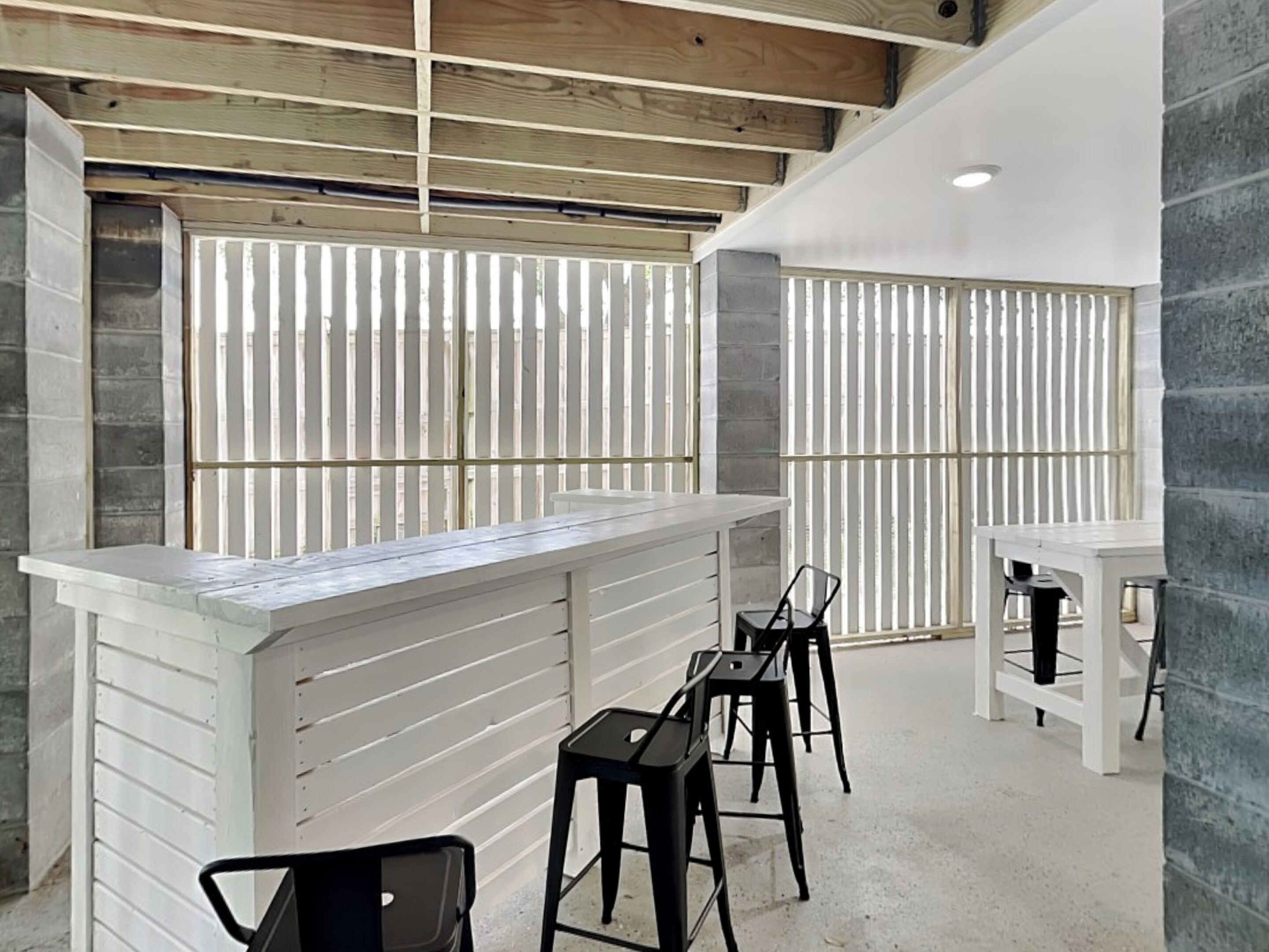 A modern bar area with a white counter and black stools.