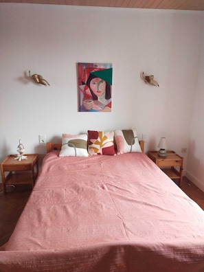 A bedroom with a large bed, two bedside tables, a wall-mounted lamp, and a painting. - Stone house 600 m from the sea with garden and terrace. (Plomodiern)