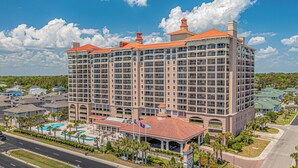 A multi-story hotel with a central courtyard, a swimming pool, and a parking area. - 3BR- 12th floor- Lake & Golf View condo|Short walk to beach| Resort Access| (North Myrtle Beach)