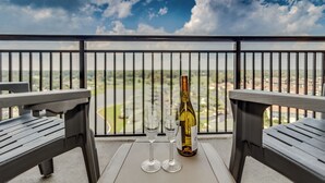 A balcony with two chairs and a table, a bottle of wine, and two wine glasses. - 3BR- 12th floor- Lake & Golf View condo|Short walk to beach| Resort Access| (North Myrtle Beach)