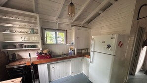 Eine Küche mit weißen Schränken, einer Holzausziehtafel, einem Spülbecken und einem Kühlschrank.