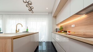 A modern kitchen with a central island, a stainless steel faucet, and a wooden countertop.