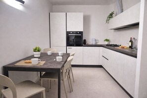 Une cuisine compacte comprenant une table à manger, des chaises, une machine à café et une petite plante.