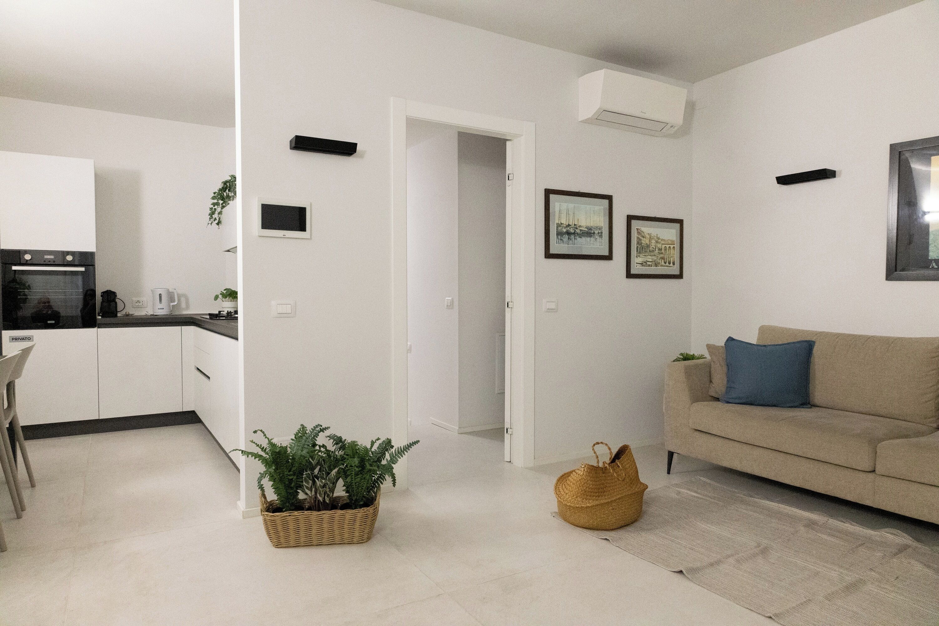 A modern living space with a kitchen, a sofa, and a dining area.