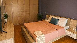 A bedroom with a bed, bedside tables, a wardrobe, and a hanging lamp.