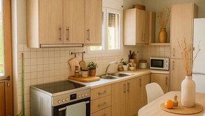 A modern kitchen with wooden cabinets, a stainless steel oven, a microwave, and a round dining table with a vase and a plant.
