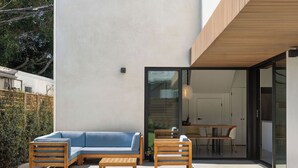 Une terrasse extérieure moderne avec un canapé bleu, des chaises en bois et une table à manger.