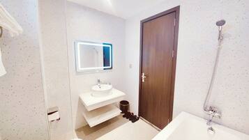 A modern bathroom with a white sink, a mirror with LED lighting, a shower, and a toilet.