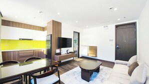 A modern living room with a glass dining table, wooden chairs, a sofa, and a coffee table. - Celina Hotel - Khach San Tam Dao (Tam Dao)