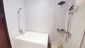 Une salle de bain avec une baignoire blanche, une douche équipée d’un pommeau de douche à main et une cabine de douche en verre.