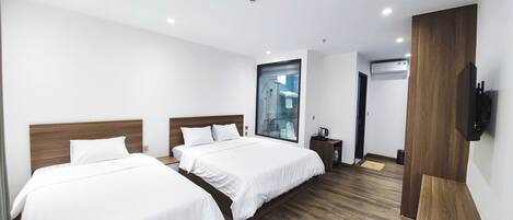 A modern hotel room with two beds, a large window, a shower, and a TV mounted on the wall.
