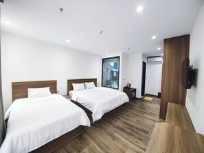 Ein modernes Hotelzimmer mit zwei Betten, einem großen Fenster, einer Dusche und einem an der Wand montierten Fernseher.