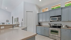 A modern kitchen with grey cabinets, stainless steel appliances, and a large island.
