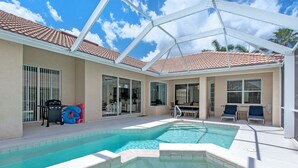 A swimming pool with a glass ceiling, outdoor seating, and a barbecue area.