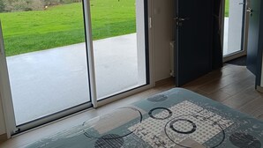 A room with a large sliding glass door leading to a green field. - Ty bugale in the heart of nature, 30 minutes from Lorient and its coast, ideal for recharging your batteries. (Inguiniel)
