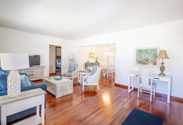 A spacious living room with a sofa, coffee table, and a TV. There is a dining area with a table and chairs. - The Hibiscus Haven~ centrally located near hospital/ downtown Stuart (Stuart)