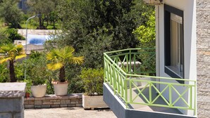 Un immeuble à plusieurs étages, doté de balcons, offrant une vue sur la mer et entouré de verdure.