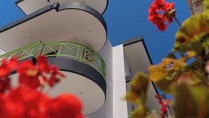Un bâtiment moderne doté d’un balcon circulaire et d’une rambarde en métal vert.