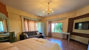 Une chambre d’hôtel avec un grand lit, un canapé, un bureau et une télévision.