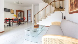 A spacious living area with a glass coffee table, a grey sofa, and a staircase with wooden railings. - La Casa Di Nico by TuscanyWeGo (Capannori)