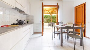 A modern kitchen with white cabinets, a gas stove, and a dining area with a table and chairs. - La Casa Di Nico by TuscanyWeGo (Capannori)