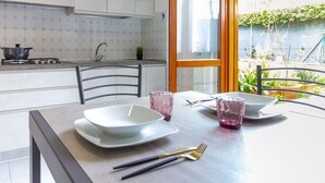 A modern kitchen with white cabinets, a gas stove, and a window overlooking a garden. - La Casa Di Nico by TuscanyWeGo (Capannori)
