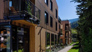 A modern building with wooden paneling and large windows, a paved pathway, and potted plants.