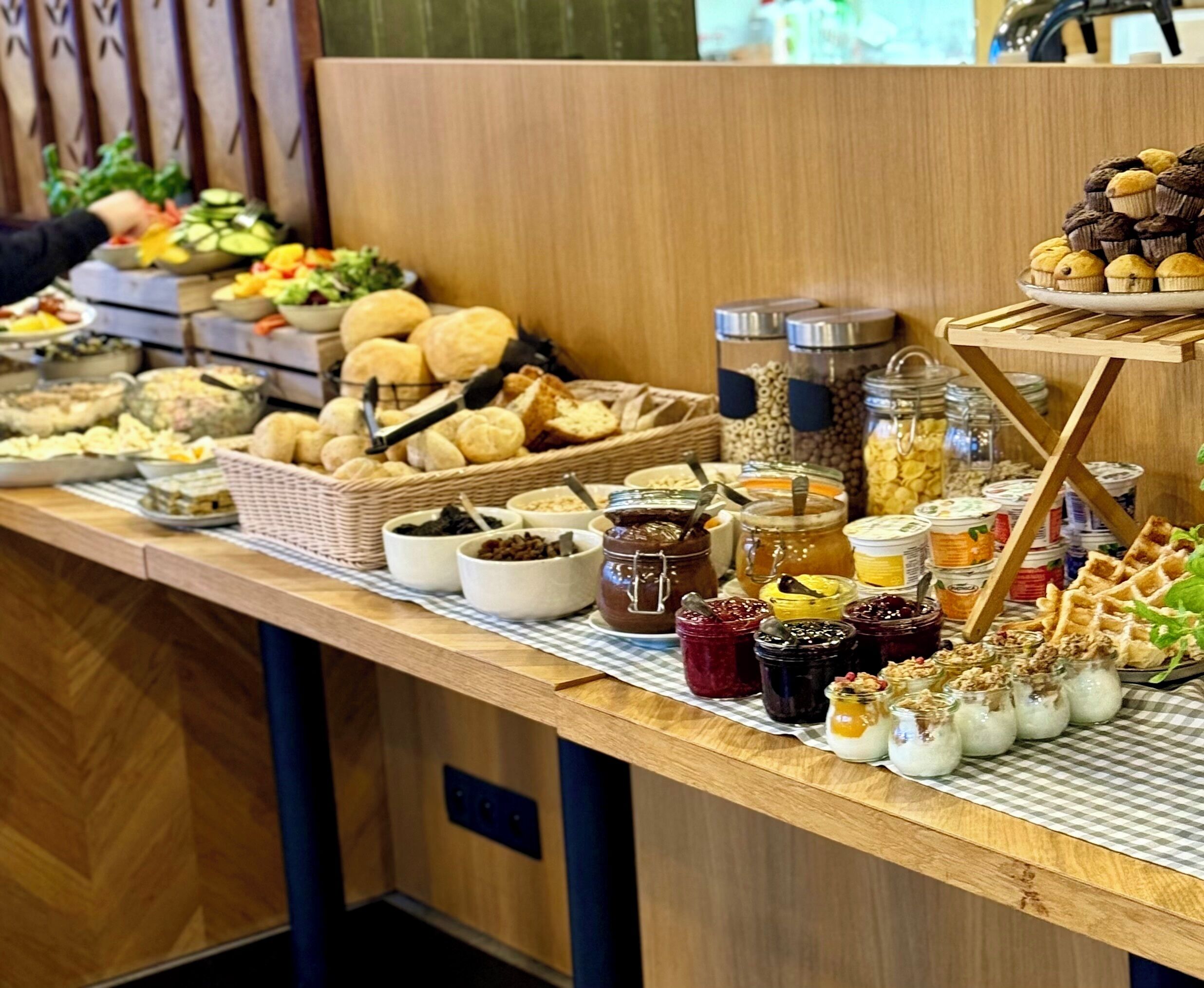 A buffet table with various food items including pastries, bread, and condiments.