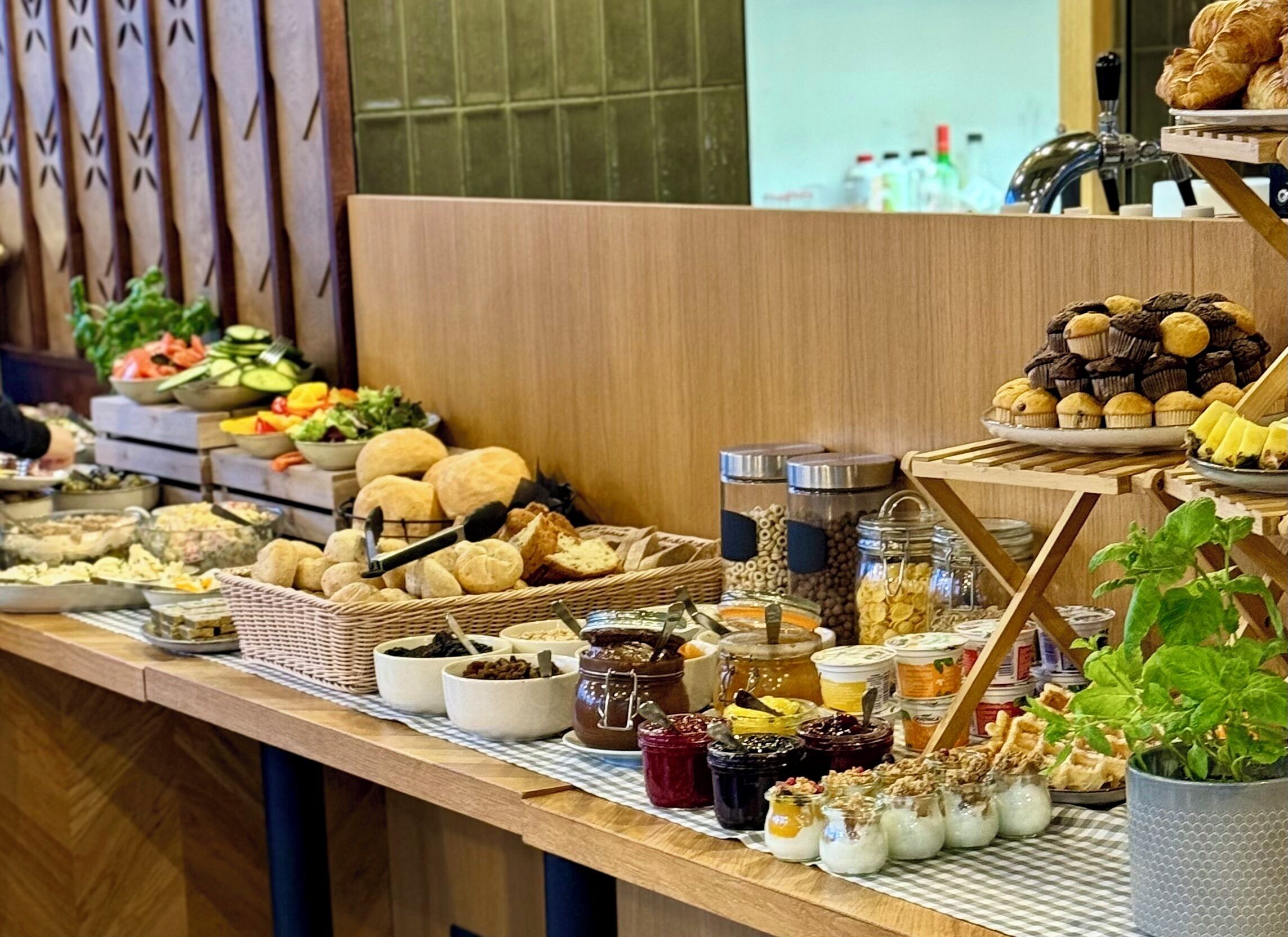 A buffet with various food items including bread, pastries, and condiments.