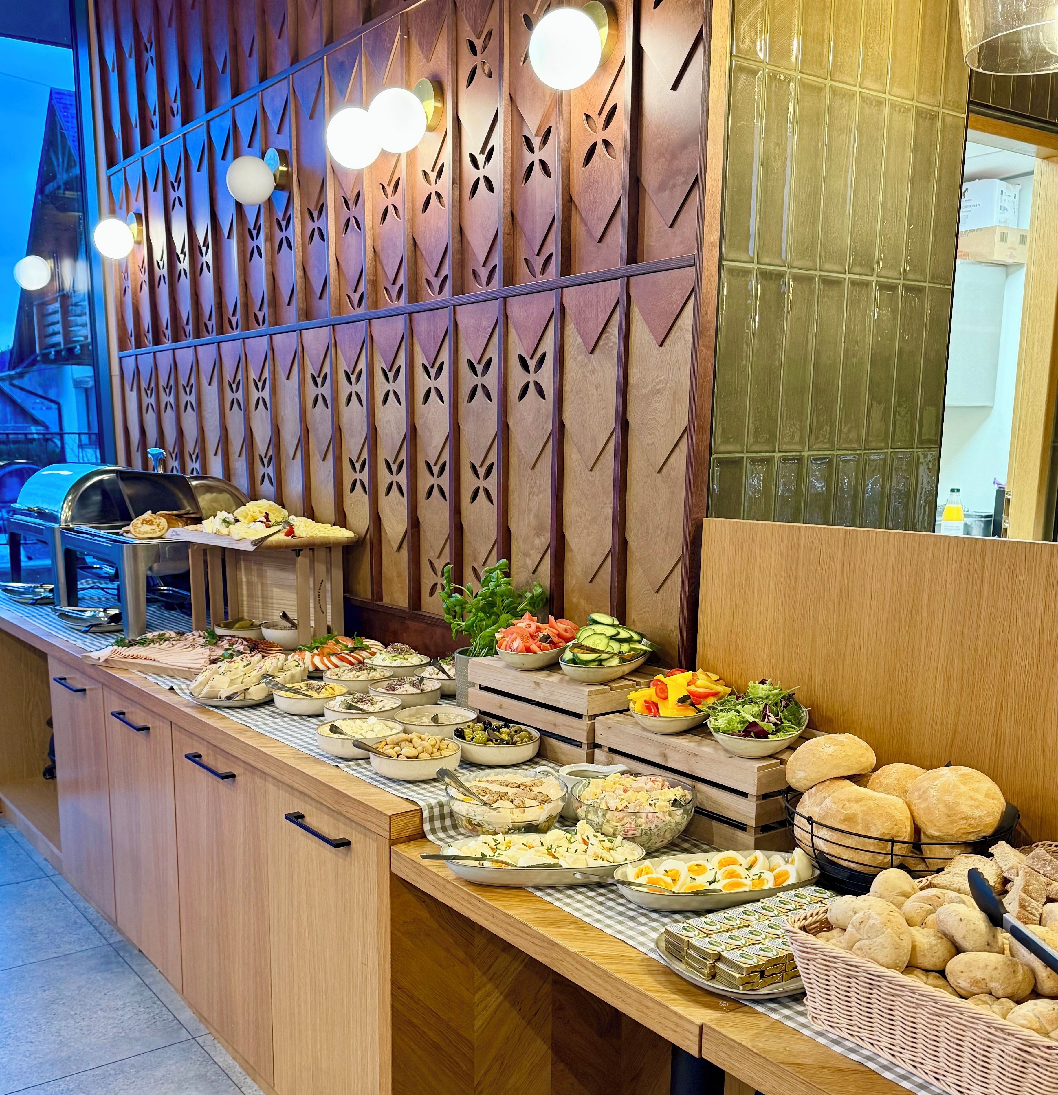 A buffet setup with various food items and a decorative wooden panel with cut-out designs.