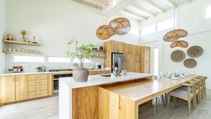 Una cocina moderna con armarios de madera, una isla grande y lámparas colgantes de ratán.