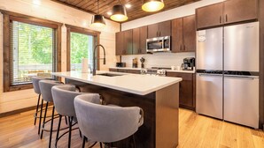 A modern kitchen with a central island, bar stools, stainless steel appliances, and wooden ceiling. - *Stunning 4BD Lodge w/ POOL + Hot Tub + Near TOWN* (Pigeon Forge)