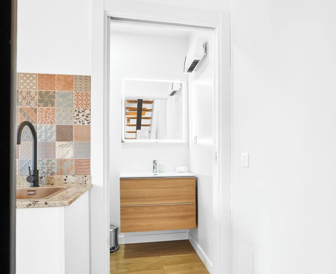 Un bagno moderno con lavandino, specchio e mobiletto in legno.