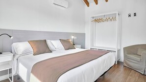 Un dormitorio moderno con cama, mesitas de noche, lámpara colgante, armario y una silla.