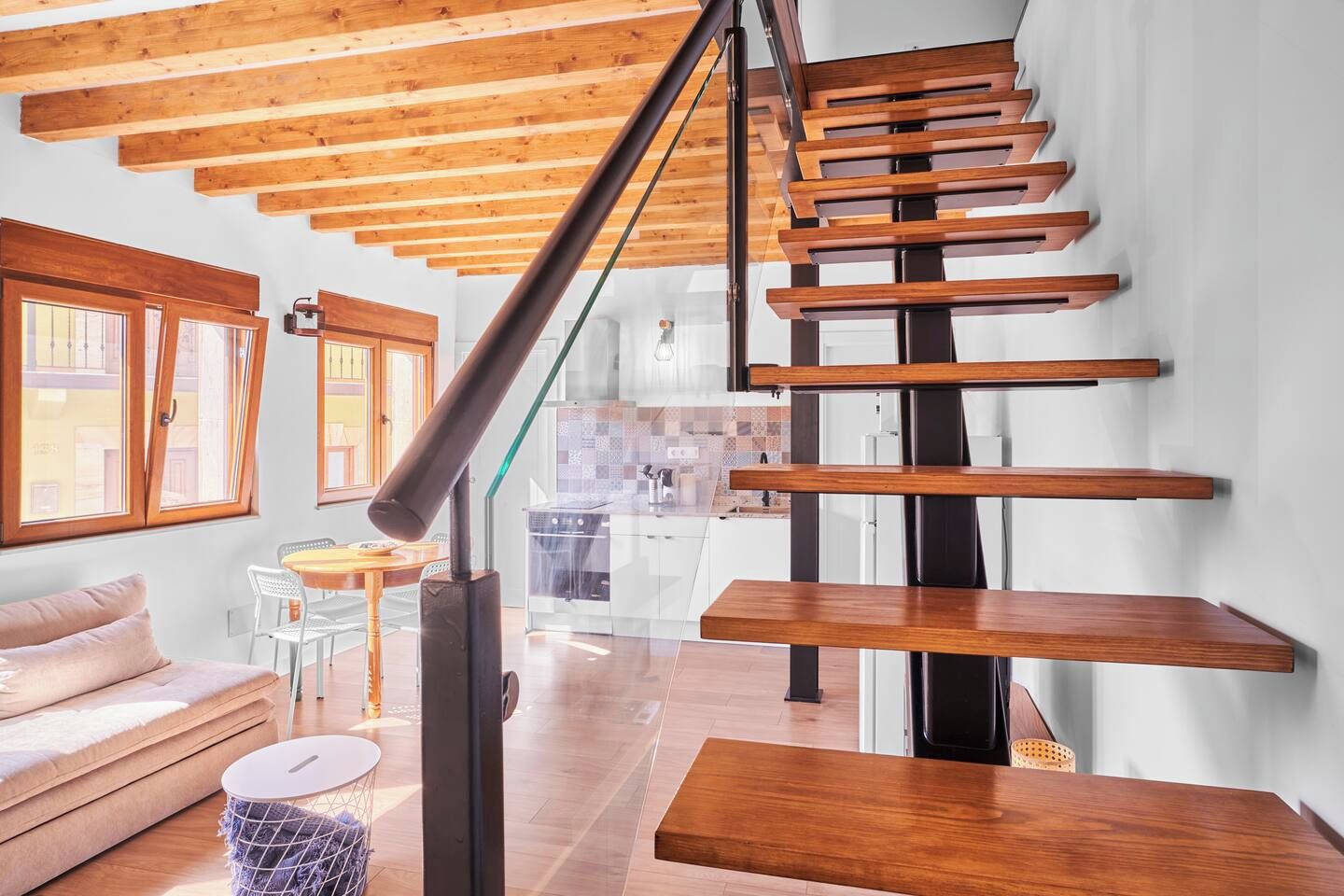 Un interior moderno con una escalera de madera, un sofá y una zona de comedor.