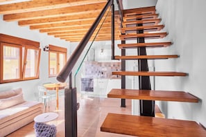 Un interior moderno con una escalera de madera, un sofá y una zona de comedor.