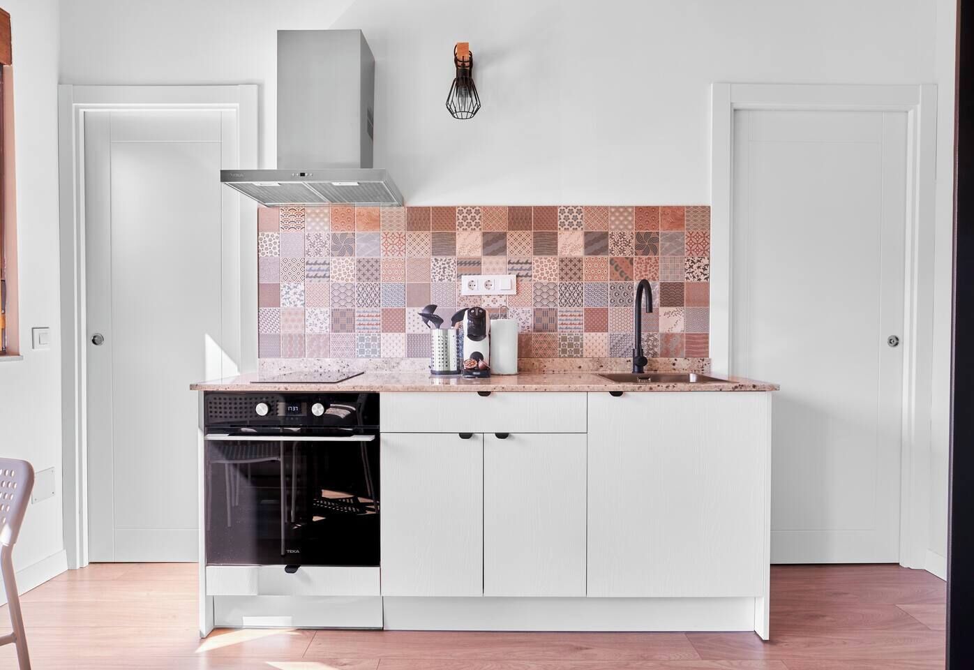 Una cocina compacta con horno integrado, pileta y un salpicadero con diseño.