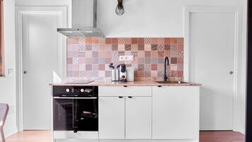 Una cocina compacta con horno integrado, pileta y un salpicadero con diseño.