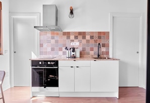 Una cocina compacta con horno integrado, pileta y un salpicadero con diseño.