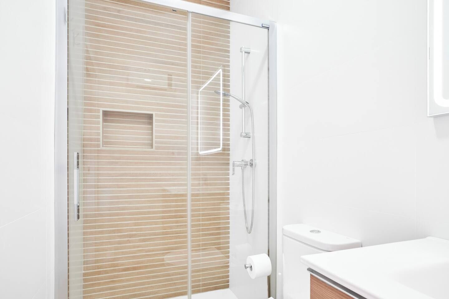 A modern bathroom with a glass shower enclosure, a toilet, and a sink.