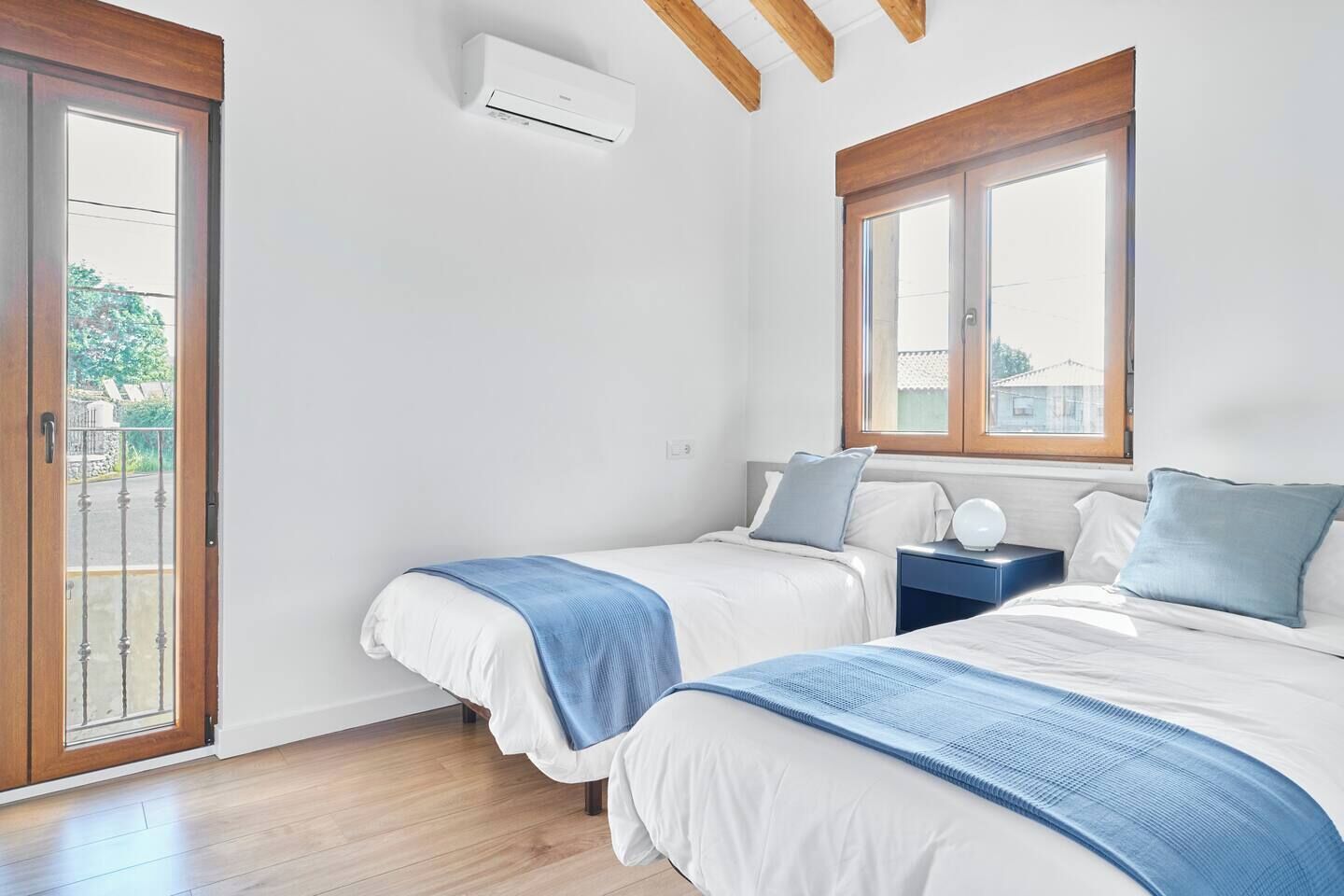 Un dormitorio con dos camas, una ventana y un equipo de aire acondicionado.