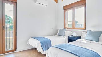 Un dormitorio con dos camas, una ventana y un equipo de aire acondicionado.