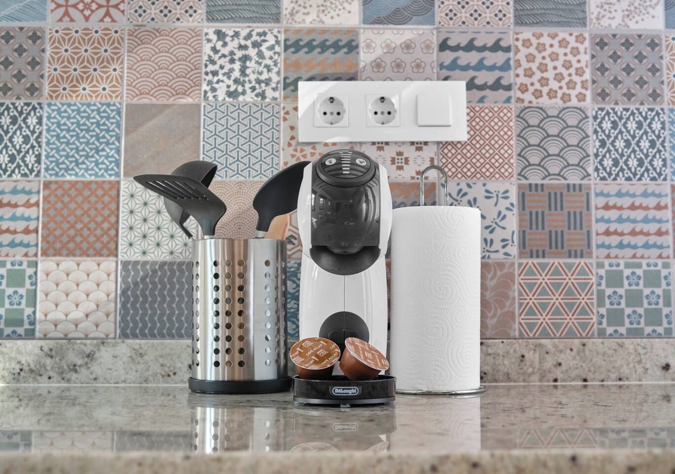 Un piano di lavoro in cucina con una macchina da caffè, un bollitore e un colino.