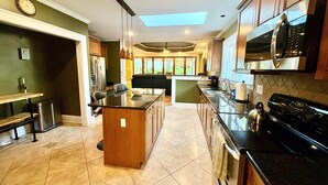 Una cocina moderna con una isla central, electrodomésticos de acero inoxidable y un tragaluz.
