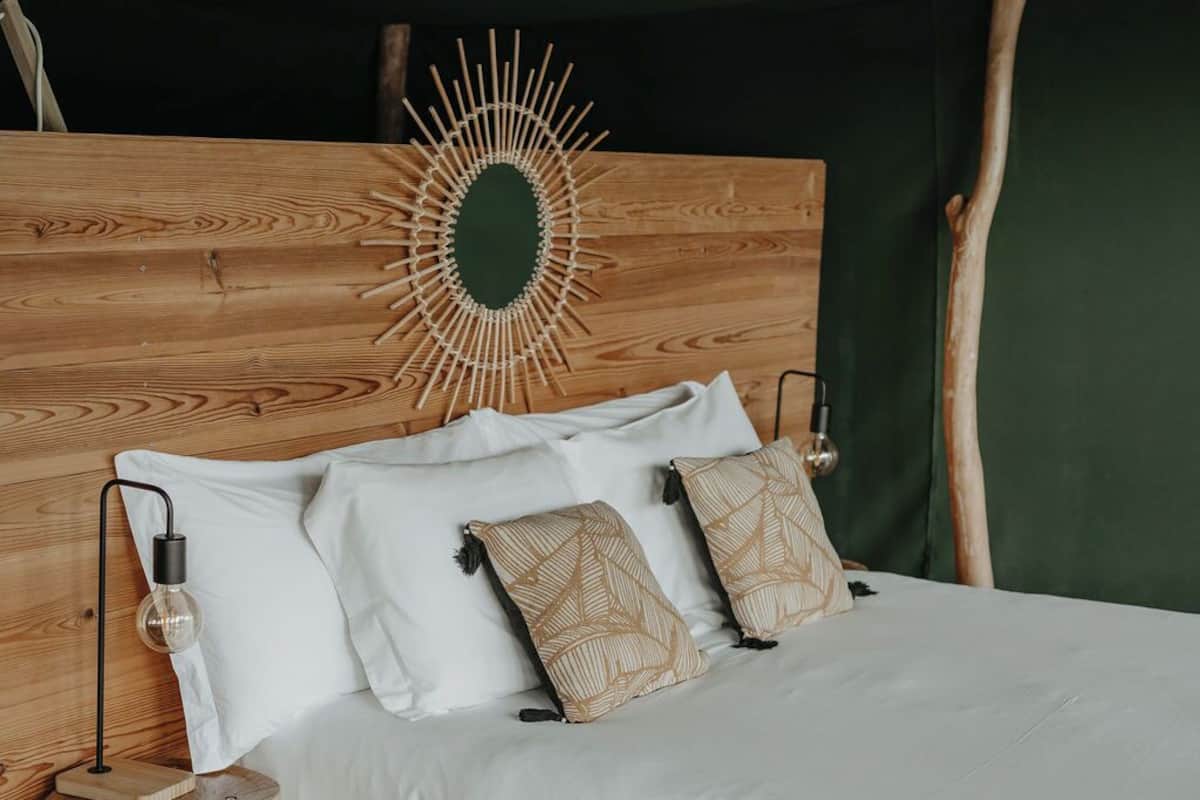 Un lit avec une tête de lit en bois, une literie blanche et des coussins à motifs.