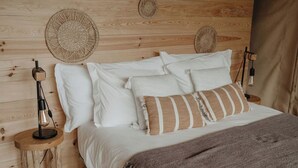 Een houten bed met wit beddengoed en een bruine plaid.