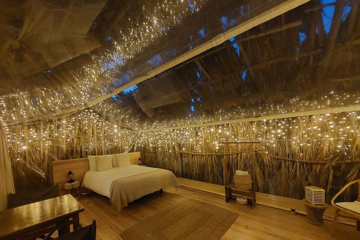 Une pièce chaleureuse avec un lit, des meubles en bois et un plafond décoré de guirlandes lumineuses.